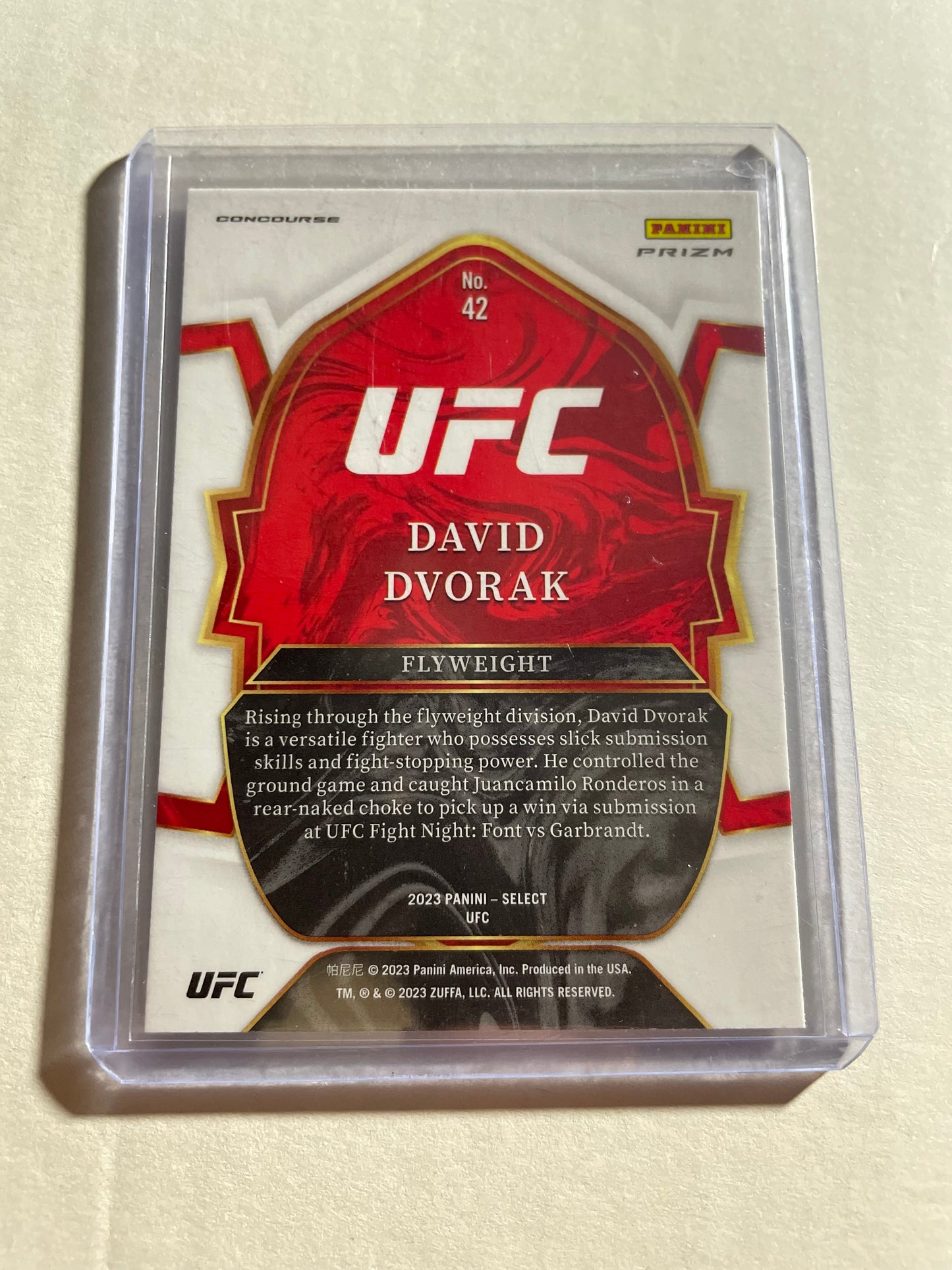 2023 Panini Select UFC David Dvorak Rookie Card from the Concourse set.The card features a vibrant tri-color prizm design with red and blue parallels.It is identified as card #42 in the set and features the official "RC" rookie logo.